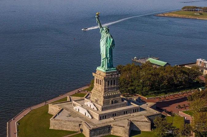 The Statue of Liberty from above on Liberty Island, a boat wake in the harbor